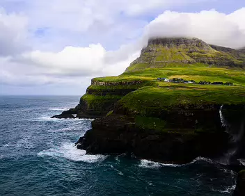 Coastal Jewel The village of Gásadalur overlooks the ocean with the Múlafossur Waterfall cascading below.
