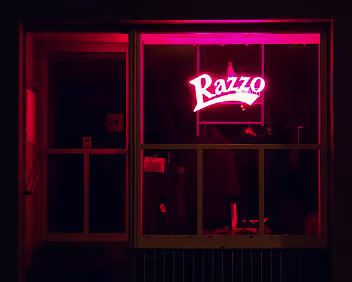 Razzo A storefront glowing in bold red neon, cutting through the darkness of the quiet street.